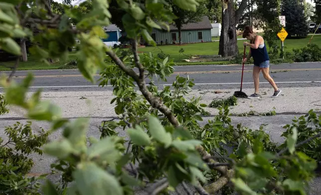 Dawn Sands cleans debris off Goddard Street on French Island after a storm with extreme winds in La Crosse, Wis., Tuesday, July 29, 2025. (Saskia Hatvany/La Crosse Tribune via AP)