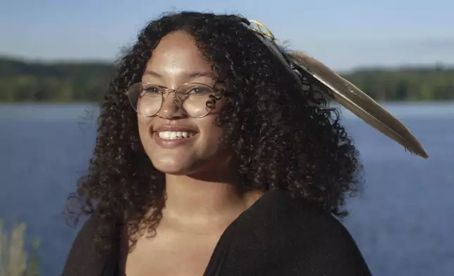 Jayvionna Buck poses for a portrait by the Mississippi River with the new bald eagle feather she received at a ceremony honoring high school graduates like her at the Prairie Island Indian Community in Minnesota on Wednesday, July 9, 2025. (AP Photo/Mark Vancleave)