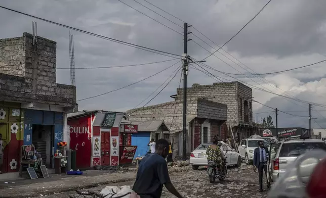 People move past an electricity pole bringing power from a solar farm in the Ndosho neighborhood of Goma, Congo, May 23, 2025. (AP Photo/Moses Sawasawa)