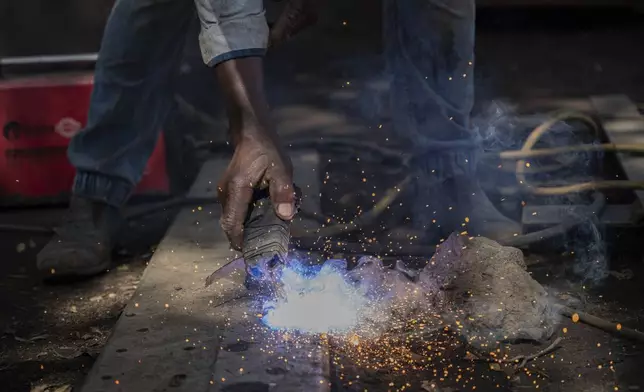 Mahamudu Bitego, a welder, whose business is powered in part by solar energy, works in Goma, Congo, May 23, 2025. (AP Photo/Moses Sawasawa)