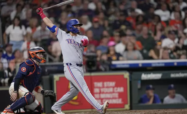 Texas Rangers' Alejandro Osuna, right, his a RBI scrifice fly as Houston Astros catcher Victor Caratini, left, watches during the fourth inning of a baseball game Sunday, July 13, 2025, in Houston. (AP Photo/David J. Phillip)