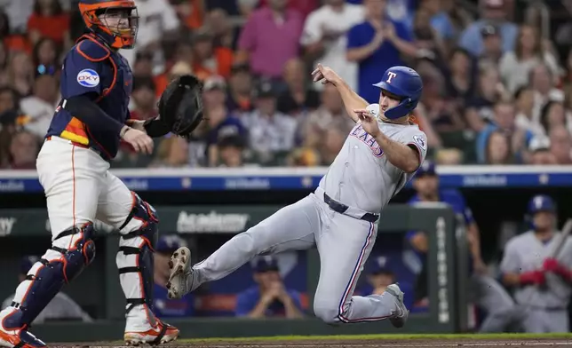 Texas Rangers' Wyatt Langford, right, scores as Houston Astros catcher Victor Caratini stands in front of home plate during the second inning of a baseball game Sunday, July 13, 2025, in Houston. (AP Photo/David J. Phillip)