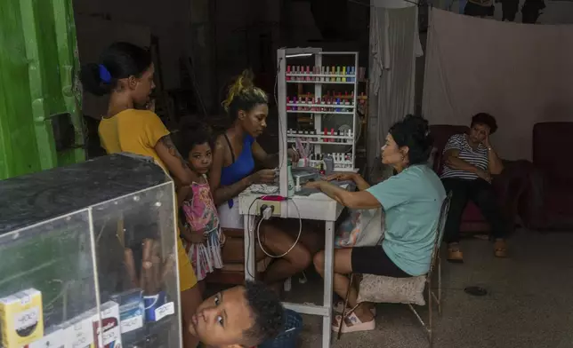 A manicurist works on a client's nails as others wait at a home-run nail salon in Havana, Cuba, Monday, July 7, 2025. (AP Photo/Ramon Espinosa)