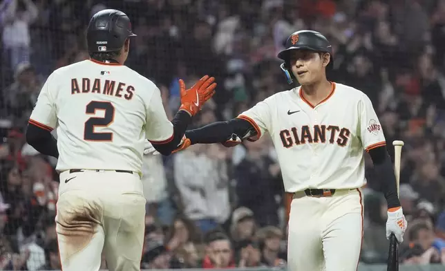 San Francisco Giants' Willy Adames (2) is congratulated by Jung Hoo Lee after scoring against the Philadelphia Phillies during the eighth inning of a baseball game in San Francisco, Monday, July 7, 2025. (AP Photo/Jeff Chiu)