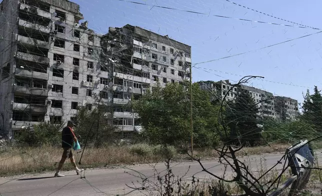 In this photo provided by Ukraine's 65th Mechanized Brigade press service, a local resident walks along the street under an anti-drone net in Orikhiv, Zaporizhzhia region, Ukraine, Tuesday, July 15, 2025. (Andriy Andriyenko/Ukraine's 65th Mechanized Brigade via AP)