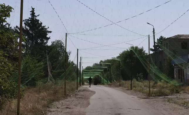 In this photo provided by Ukraine's 65th Mechanized Brigade press service, a local resident walks along the street under an anti-drone net in Orikhiv, Zaporizhzhia region, Ukraine, Tuesday, July 15, 2025. (Andriy Andriyenko/Ukraine's 65th Mechanized Brigade via AP)