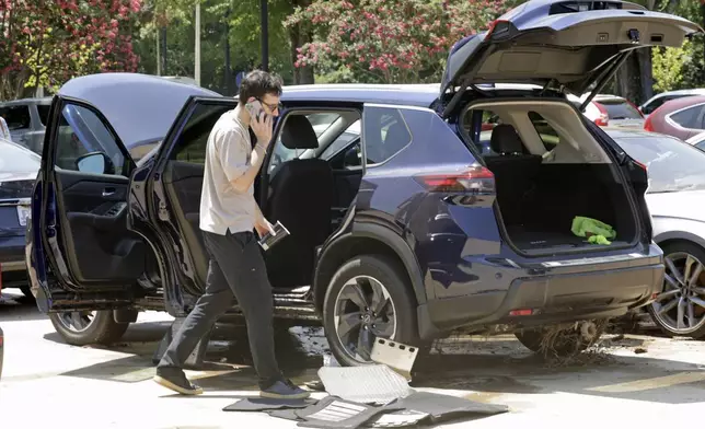 A man tries to dry his car out in a parking lot at University Place shopping center after it was flooded out during tropical storm Chantal, Monday, July 7, 2025, in Chapel Hill, N.C. (AP Photo/Chris Seward)