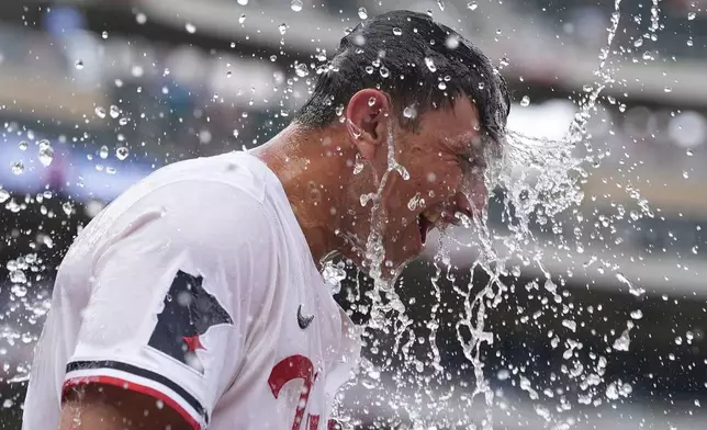 Minnesota Twins' Brooks Lee is doused after reaching on a winning infield RBI bunt to score teammate Byron Buxton during the ninth inning of a baseball game against the Tampa Bay Rays, Saturday, July 5, 2025, in Minneapolis. (AP Photo/Abbie Parr)