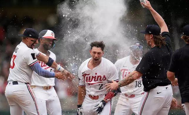 Minnesota Twins' Brooks Lee (2) celebrates with teammates after reaching on a winning infield RBI bunt to score teammate Byron Buxton during the ninth inning of a baseball game against the Tampa Bay Rays Saturday, July 5, 2025, in Minneapolis. (AP Photo/Abbie Parr)