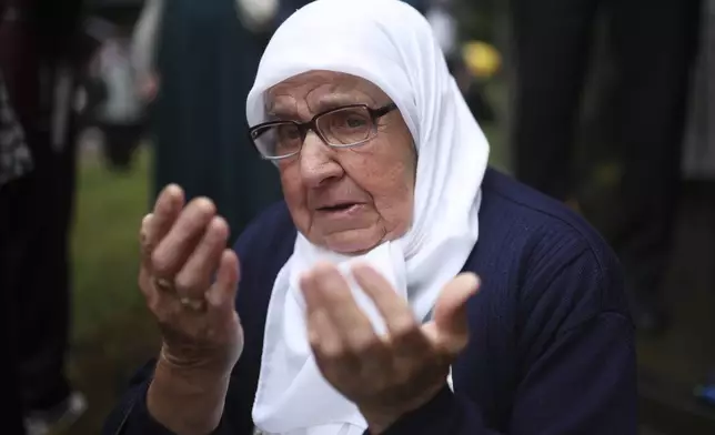 A Muslim women prays next to a truck carrying remains of the identified victims of the 1995 Srebrenica massacre to the Memorial centre in Potocari, where they will be buried on July 11, in Visoko, Bosnia, Wednesday, July 9, 2025. (AP Photo/Armin Durgut)