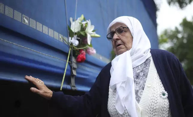 A woman touches a truck carrying remains of the identified victims of the 1995 Srebrenica massacre to the Memorial centre in Potocari, where they will be buried on July 11, in Visoko, Bosnia, Wednesday, July 9, 2025. (AP Photo/Armin Durgut)