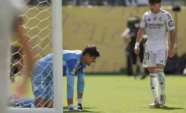 Real Madrid's Thibaut Courtois kneels on the ground besides team mate Fran Garcia during the Club World Cup semifinal soccer match between PSG and Real Madrid in East Rutherford, N.J., Wednesday, July 9, 2025. (AP Photo/Adam Hunger)