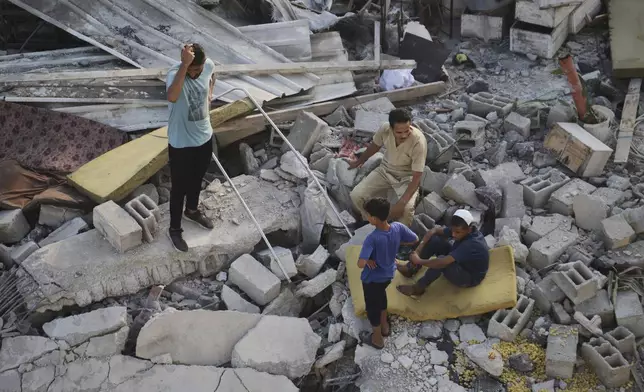 Palestinians inspect the site struck by an Israeli bombardment in Muwasi, Khan Younis, Gaza Strip, Monday, July 28, 2025. (AP Photo/Mariam Dagga)