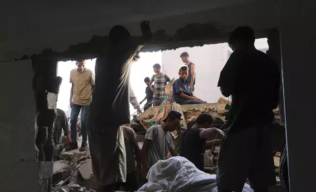Palestinians inspect the site struck by an Israeli bombardment in Muwasi, Khan Younis, Gaza Strip, Monday, July 28, 2025. (AP Photo/Mariam Dagga)