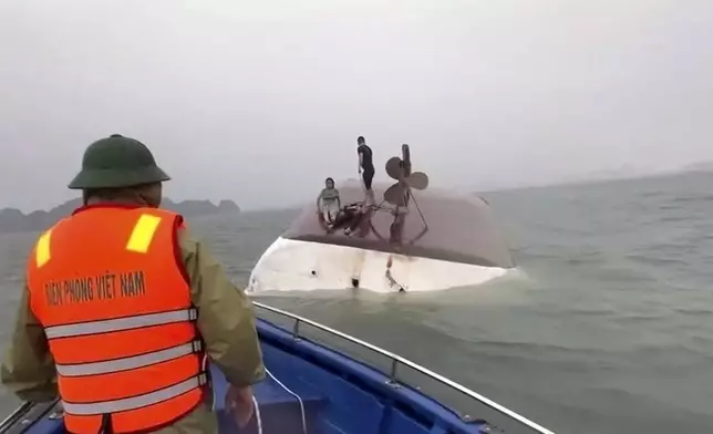 This image from a video provided by QDND shows people on a capsized tourist boat being rescued in Ha Long Bay, Vietnam on Saturday, July 19, 2025. (QDND via AP)