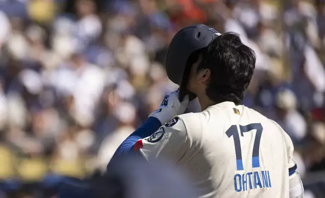 Los Angeles Dodgers' Shohei Ohtani puts on his batting helmet during the first inning of a baseball game against the Houston Astros in Los Angeles, Saturday, July 5, 2025. (AP Photo/Kyusung Gong)