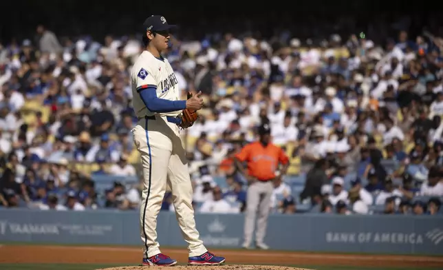 Los Angeles Dodgers starting pitcher Shohei Ohtani, foreground, gestures during the second inning of a baseball game against the Houston Astros in Los Angeles, Saturday, July 5, 2025. (AP Photo/Kyusung Gong)