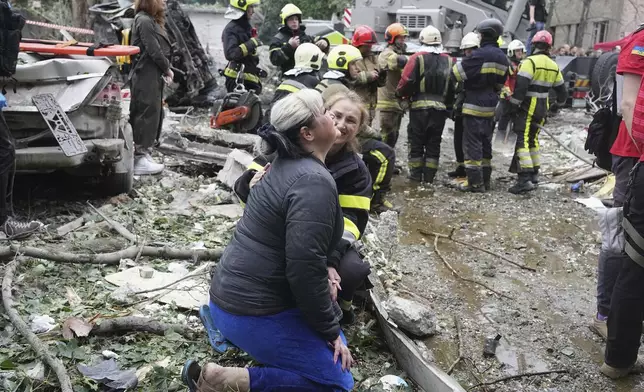 A woman is comforted by servicewoman as she cries at the scene of a night Russian missile attack in Kyiv, Ukraine, Thursday, July 31, 2025. (AP Photo/Efrem Lukatsky)
