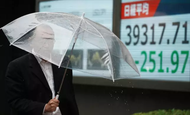 A person walks in front of an electronic stock board showing Japan's Nikkei index at a securities firm Monday, July 14, 2025, in Tokyo. (AP Photo/Eugene Hoshiko)