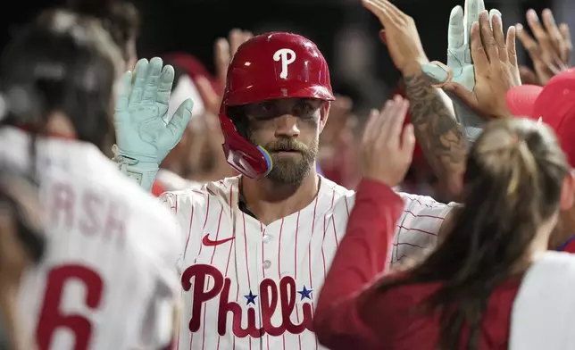 Philadelphia Phillies' Bryce Harper celebrates in the dugout after hitting a two-run home run during the eighth inning of a baseball game against the Los Angeles Angels Saturday, July 19, 2025, in Philadelphia. (AP Photo/Matt Slocum)