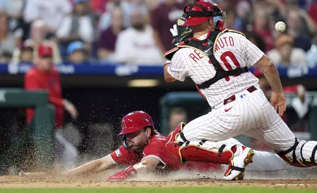 Los Angeles Angels' Nolan Schanuel, left, scores past Philadelphia Phillies catcher J.T. Realmuto on a double by Taylor Ward during the seventh inning of a baseball game Saturday, July 19, 2025, in Philadelphia. (AP Photo/Matt Slocum)