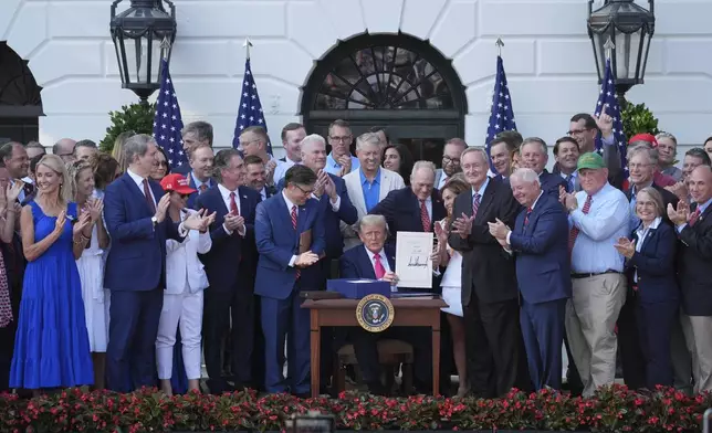 President Donald Trump signs his signature bill of tax breaks and spending cuts at the White House, Friday, July 4, 2025, in Washington, surrounded by members of Congress. (AP Photo/Evan Vucci)