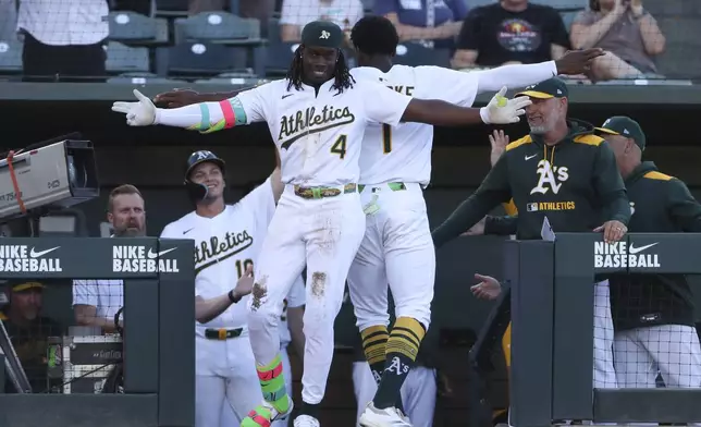 Athletics' Lawrence Butler (4) celebrates with teammate Denzel Clarke (1) after hitting an inside-the-park home run against the Atlanta Braves during the first inning of a baseball game Tuesday, July 8, 2025, in West Sacramento, Calif. (AP Photo/Scott Marshall)