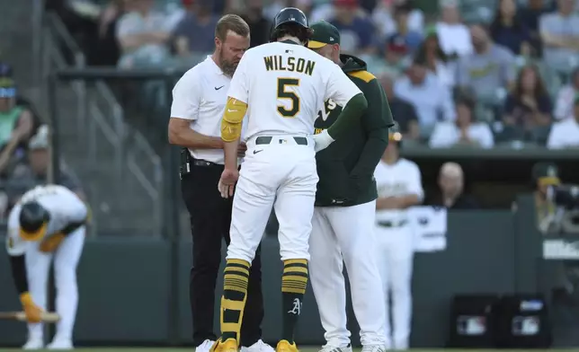 The Athletics trainer and manager Mark Kotsay, right, come to check on Athletics' Jacob Wilson (5) after he is hit by the pitch during the first inning of a baseball game against the Atlanta Braves, Tuesday, July 8, 2025, in West Sacramento, Calif. Wilson would go on to leave the game. (AP Photo/Scott Marshall)