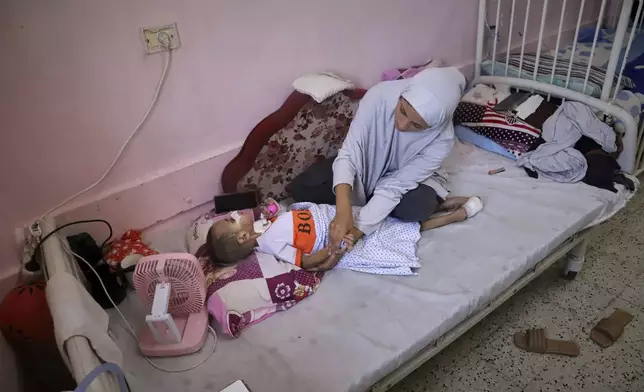 Nour al-Hams cares for her 3-year-old nephew, Amr al-Hams, who lies in a hospital bed with brain damage caused by an Israeli strike on his family's tent in April, at Nasser Hospital in Khan Younis, Gaza Strip, Wednesday, June 25, 2025. (AP Photo/Mariam Dagga)