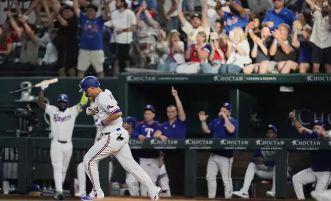 The dugout and fans cheer after Texas Rangers' Corey Seager, front, hit a solo home run in the third inning of a baseball game against the Athletics, Wednesday, July 23, 2025, in Arlington, Texas. (AP Photo/Tony Gutierrez)