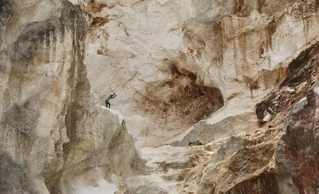 A worker pounds into rock to make gravel and sand in Kenscoff, a neighborhood of Port-au-Prince, Haiti, Thursday, July 24, 2025. (AP Photo/Odelyn Joseph)