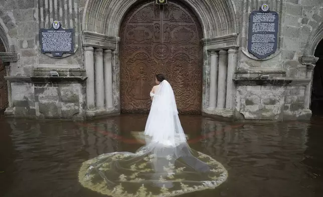 Bride Jamaica Aguilar prepares to enter the flooded Barasoain church for her wedding in Malolos, Bulacan province, Philippines on Tuesday, July 22, 2025. (AP Photo/Aaron Favila)