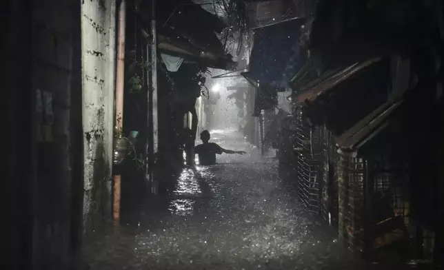 A man wades through waist-deep water in a residential area after Tropical Storm Wipha caused intensified monsoon rains that bought flooding in Quezon City, Philippines, on Monday, July 21, 2025. (AP Photo/Aaron Favila)