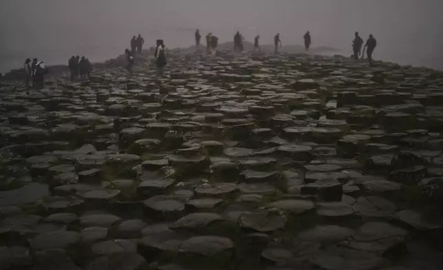 Tourists visit the Giant's Causeway near Bushmills, County Antrim, Northern Ireland, Monday, July 21, 2025. (AP Photo/Francisco Seco)