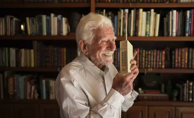Martin Cooper, who led the team that built the first mobile cellphone, sits behind a prototype of that phone at his home, April 4, 2025, in San Diego. (AP Photo/Gregory Bull)