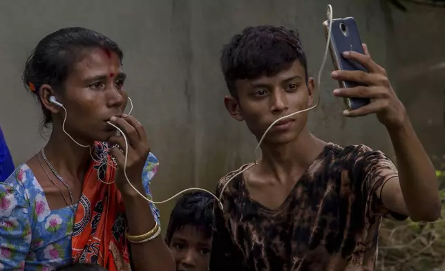 FILE - Sarasvati Devi talks to her mother in Myanmar via video call as Ranjan, her brother, holds the phone, outside a camp for Hindu refugees near Kutupalong, Bangladesh, Sept. 26, 2017. (AP Photo/Dar Yasin, File)