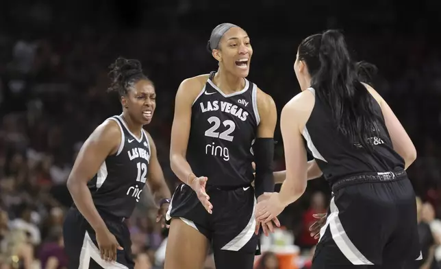 Las Vegas Aces center A'ja Wilson (22) celebrates with guard Chelsea Gray (12) and center Megan Gustafson, right, after making a basket and drawing a foul during the first half of a WNBA basketball game against the Golden State Valkyries, Saturday, July 12, 2025, in Las Vegas. (Steve Marcus/Las Vegas Sun via AP)