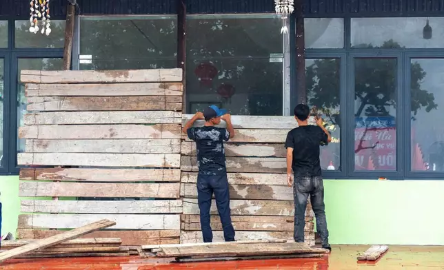 People reinforce doors ahead of Typhoon Wipha in Hai Phong, Vietnam on Monday, July 21, 2025. (Le Tan/VNExpress via AP)