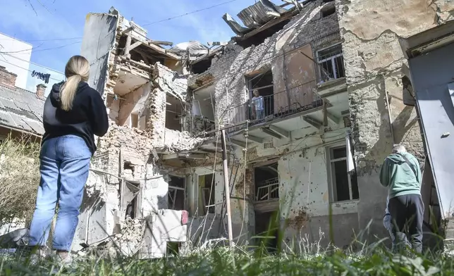 People look at a damaged residential building following Russian air attack in Lviv, Ukraine, Saturday, July 12, 2025. (AP Photo/Mykola Tys)