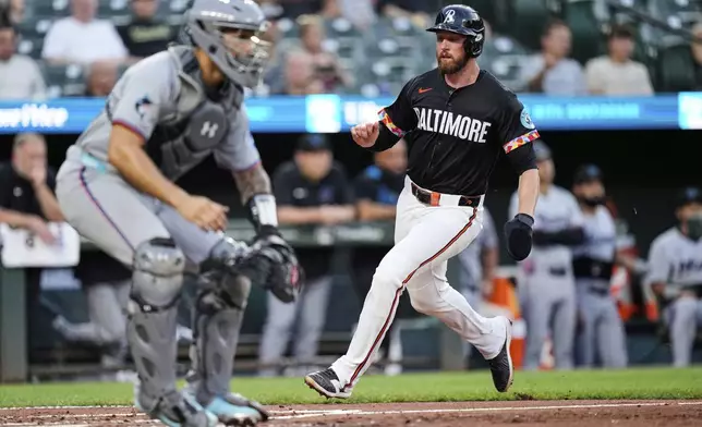 Baltimore Orioles' Jordan Westburg, right, scores past Miami Marlins catcher Agustin Ramirez, left, on an RBI hit by Ryan O'Hearn during the third inning of a baseball game, Friday, July 11, 2025, in Baltimore. (AP Photo/Stephanie Scarbrough)