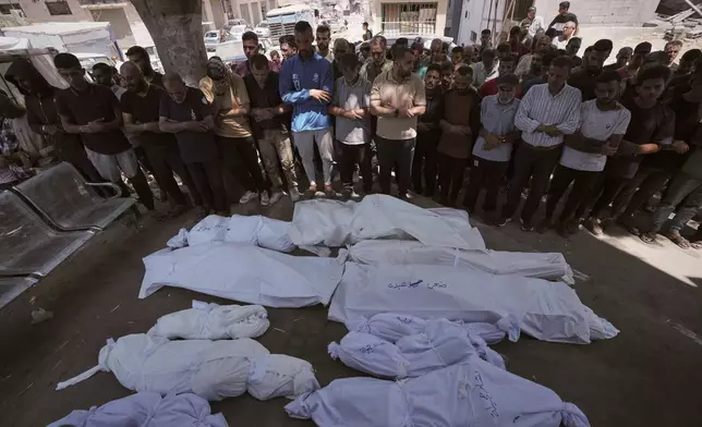 Mourners pray beside the bodies of Palestinians that were killed by an Israeli airstrike that struck a school used as a shelter, in Shifa Hospital in Gaza City, on Thursday, July 3, 2025. (AP Photo/Jehad Alshrafi)