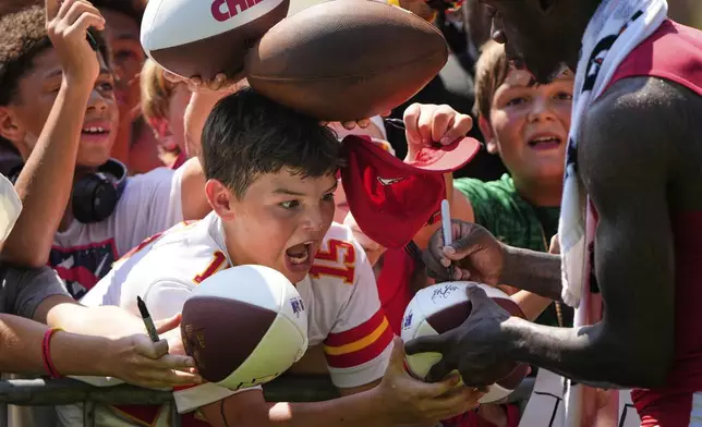 Fans react as Kansas City Chiefs wide receiver Xavier Worthy, right, gives autographs during Back Together Weekend at the team's NFL football training camp Sunday, July 27, 2025, in St. Joseph, Mo. (AP Photo/Charlie Riedel)