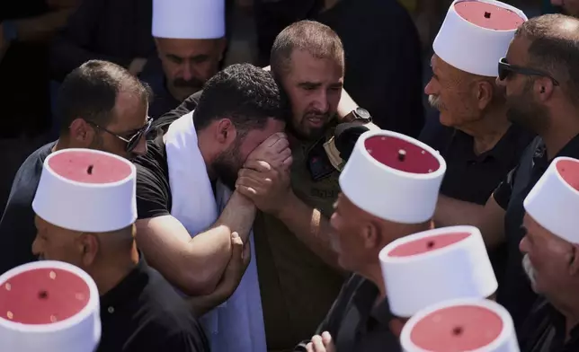Relatives of Druze Israeli captain Amir Saad, who was killed in a battle in the Gaza Strip, mourn during his funeral in the village of Yanuh Jat, northern Israel, Sunday, July 27, 2025. (AP Photo/Ariel Schalit)
