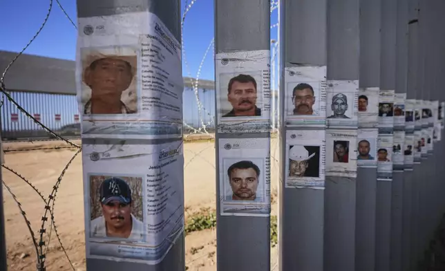Posters for missing people line the border wall separating Mexico and the United States near where it meets the Pacific Ocean Friday, July 25, 2025, in Tijuana, Mexico. (AP Photo/Gregory Bull)