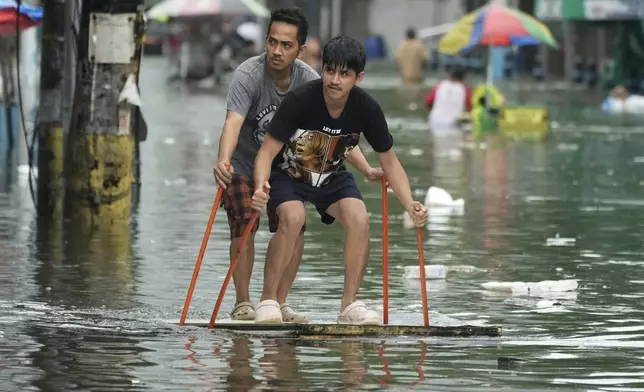 Residents use poles as they ride an improvised float along a flooded road as Typhoon Co-may intensified seasonal monsoon rains at Malabon city, Philippines on Friday, July 25, 2025. (AP Photo/Aaron Favila)