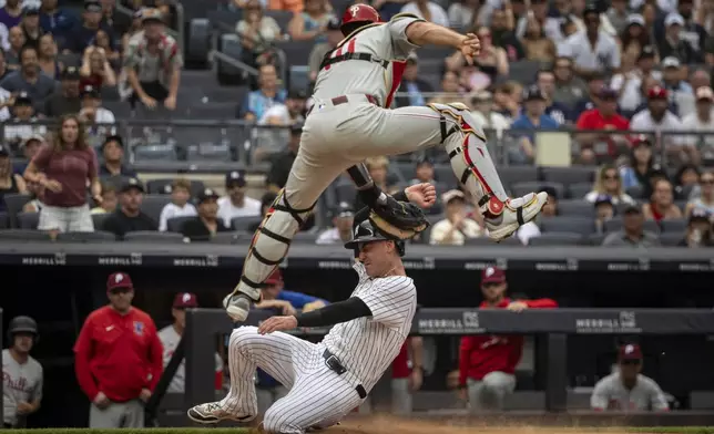 New York Yankees' Cody Bellinger, bottom, is tagged out at home plate by Philadelphia Phillies catcher J.T. Realmuto, top, during the third inning of a baseball game, Sunday, July 27, 2025, in New York. (AP Photo/Angelina Katsanis)