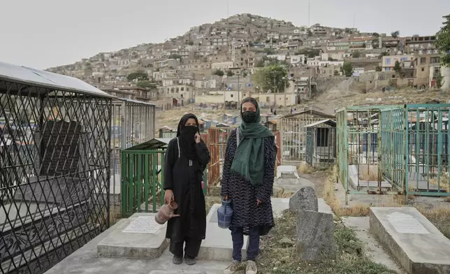 Nahideh, 13, left, an Afghan girl, stands with her friend as they wait for customers to buy water at a cemetery in Kabul, Afghanistan, Tuesday, May 27, 2025. (AP Photo/Ebrahim Noroozi)