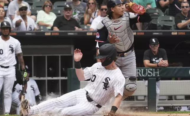 Chicago White Sox's Chase Meidroth, bottom, scores on a one-run single by Austin Slater as Cleveland Guardians catcher Bo Naylor looks to the field during the fifth inning of a baseball game in Chicago, Sunday, July 13, 2025. (AP Photo/Nam Y. Huh)