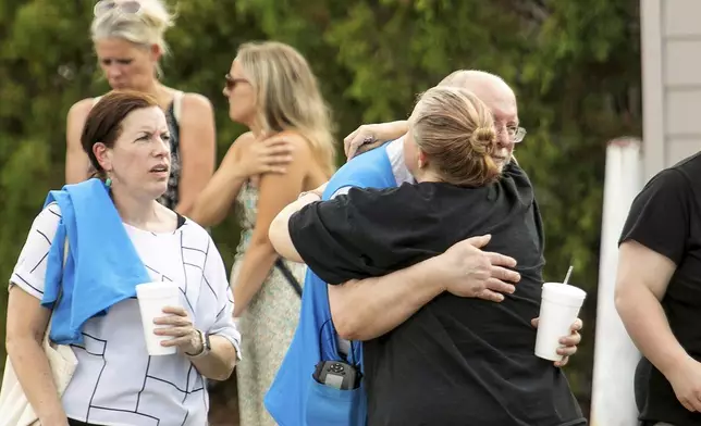 Walmart employees and customers wait outside while law enforcement investigates the scene after a stabbing incident in Traverse City, Mich., Saturday July 26, 2025. (Jan-Michael Stump/Traverse City Record-Eagle via AP)