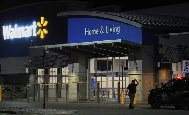 Law enforcement officers cross caution tape outside a Walmart where 11 people were stabbed in a violent attack Saturday, July 26, 2025, in Traverse City, Mich (AP Photo/Ryan Sun)